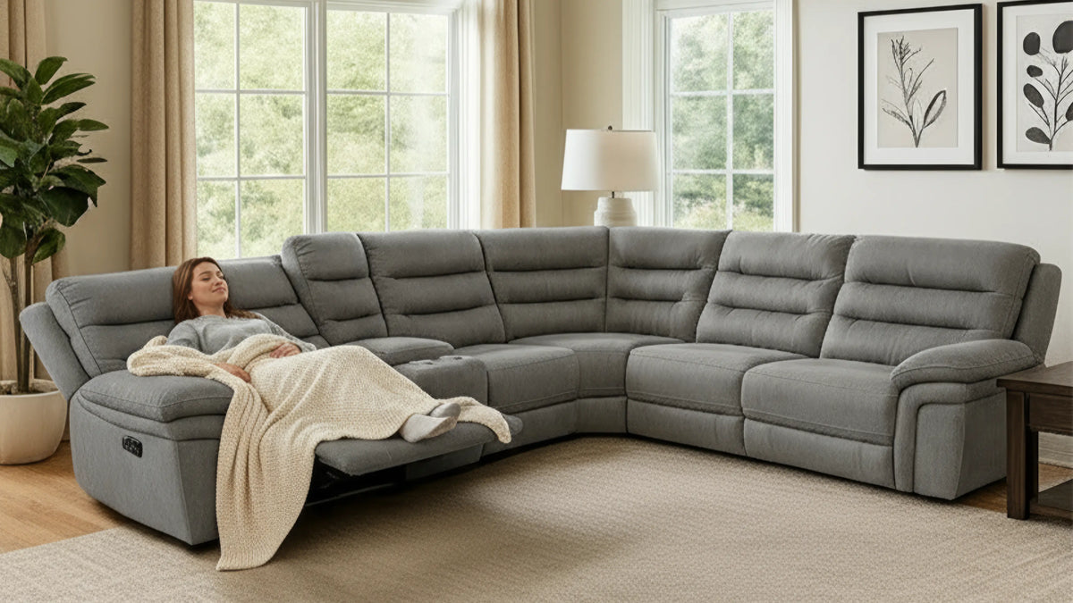 A woman is sitting on a cozy sectional under a blanket.
