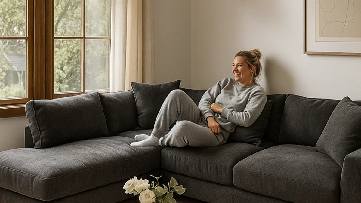 A woman is sitting on a cozy sectional  sofa while reading book