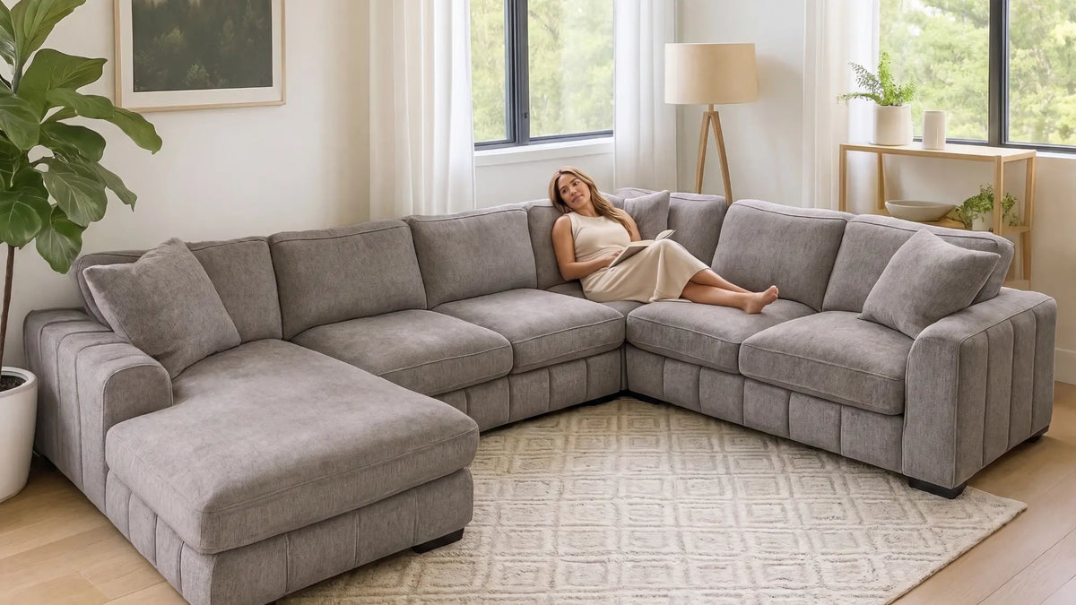 A woman lying cozy and reading a book in a u-shaped sofa
